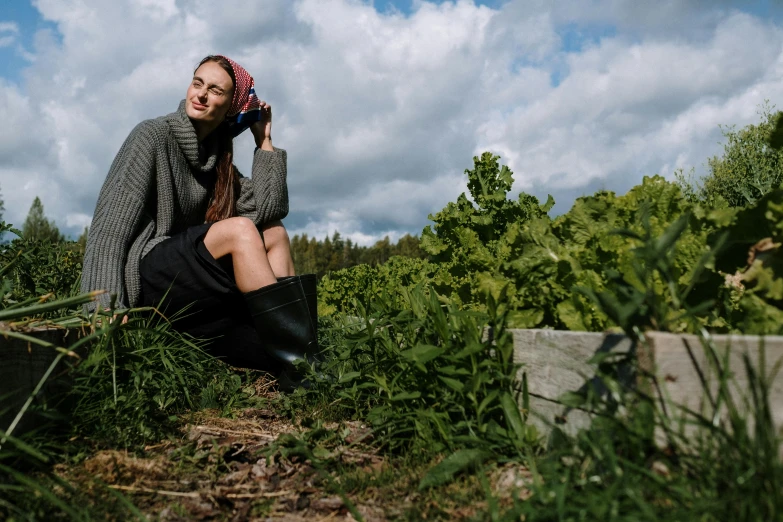 a woman sitting in the grass talking on a cell phone, by Emma Andijewska, unsplash, renaissance, outside in a farm, foliage clothing, portrait image, on a hill