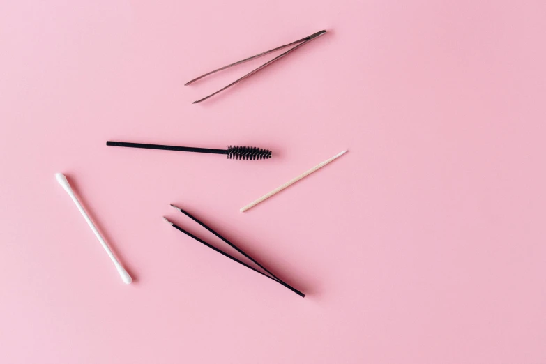 makeup brushes on a pink background, by Emma Andijewska, minimalism, eyebrow scar, thumbnail, tiny sticks, black eyeliner