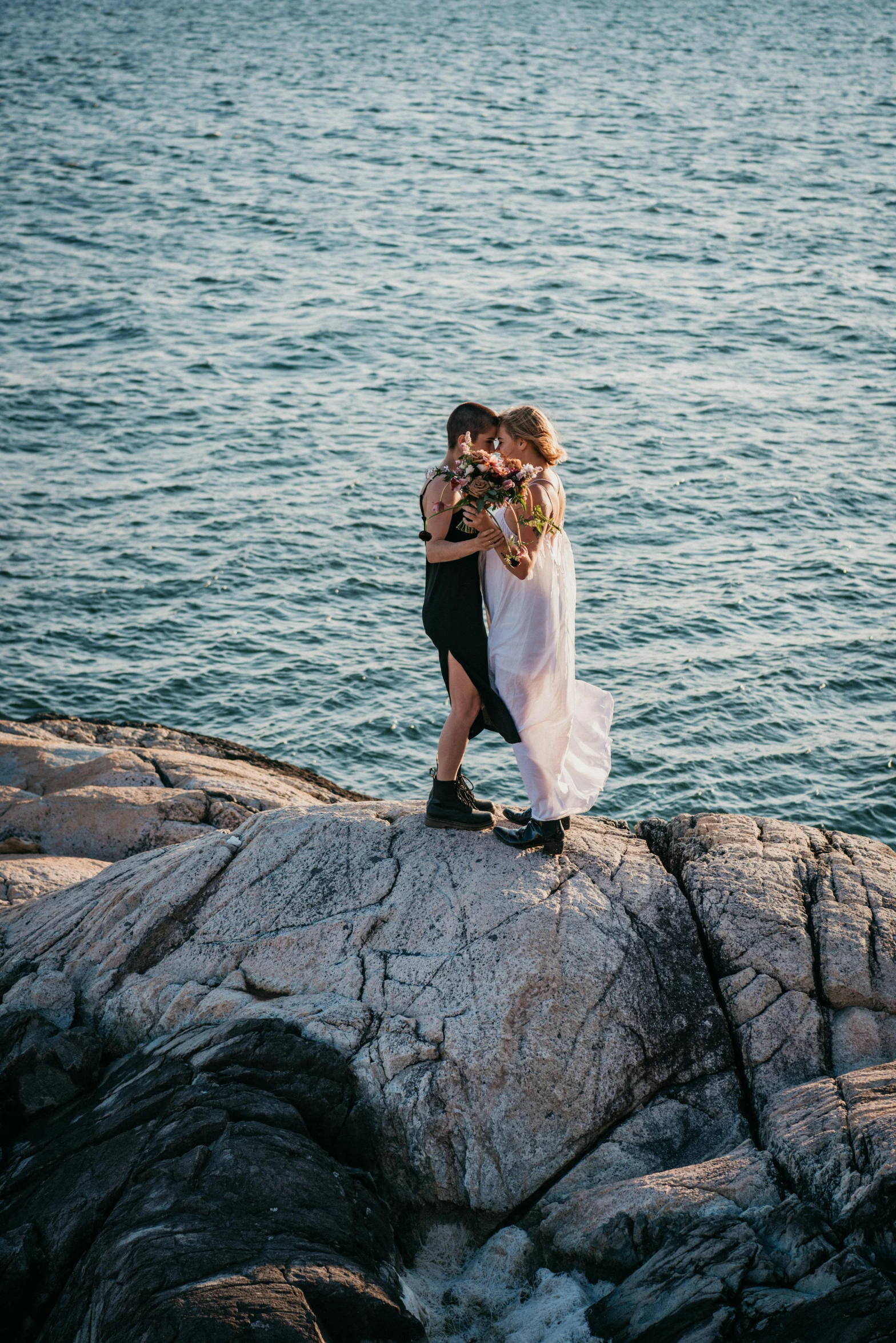 a bride and groom standing on a rock in front of the ocean, unsplash, romanticism, lesbian kiss, manly, floating bouquets, multiple stories