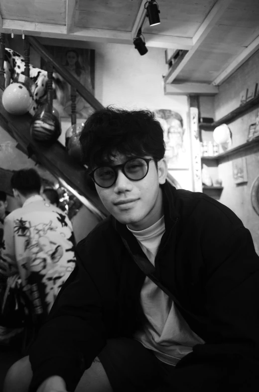 a black and white photo of a man holding a baseball bat, a black and white photo, inspired by Kim Myeong-guk, tumblr, realism, in a bright cafe, !!wearing modern glasses!!, photo from the 80s, profile picture