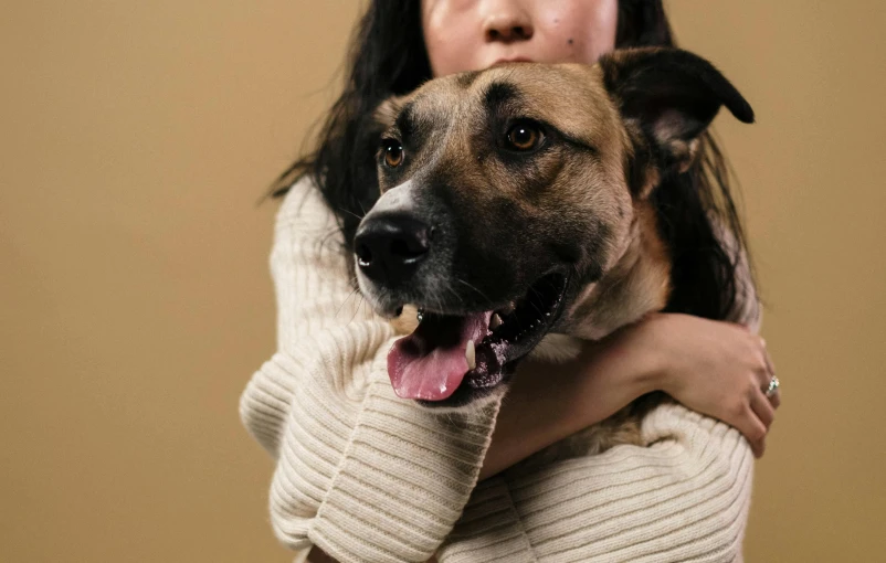 a woman holding a dog in her arms, pexels contest winner, plain background, strong chin, manuka, thumbnail