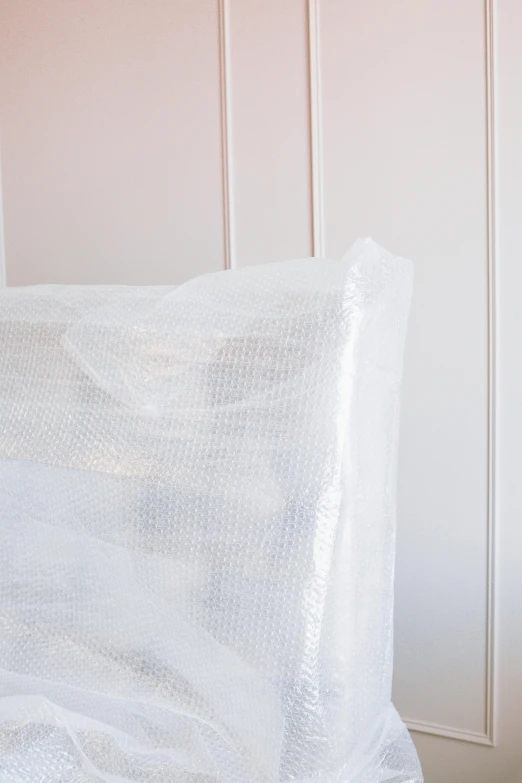 a white bed sitting in a bedroom next to a wall, plastic wrap, on clear background, promo image, upclose