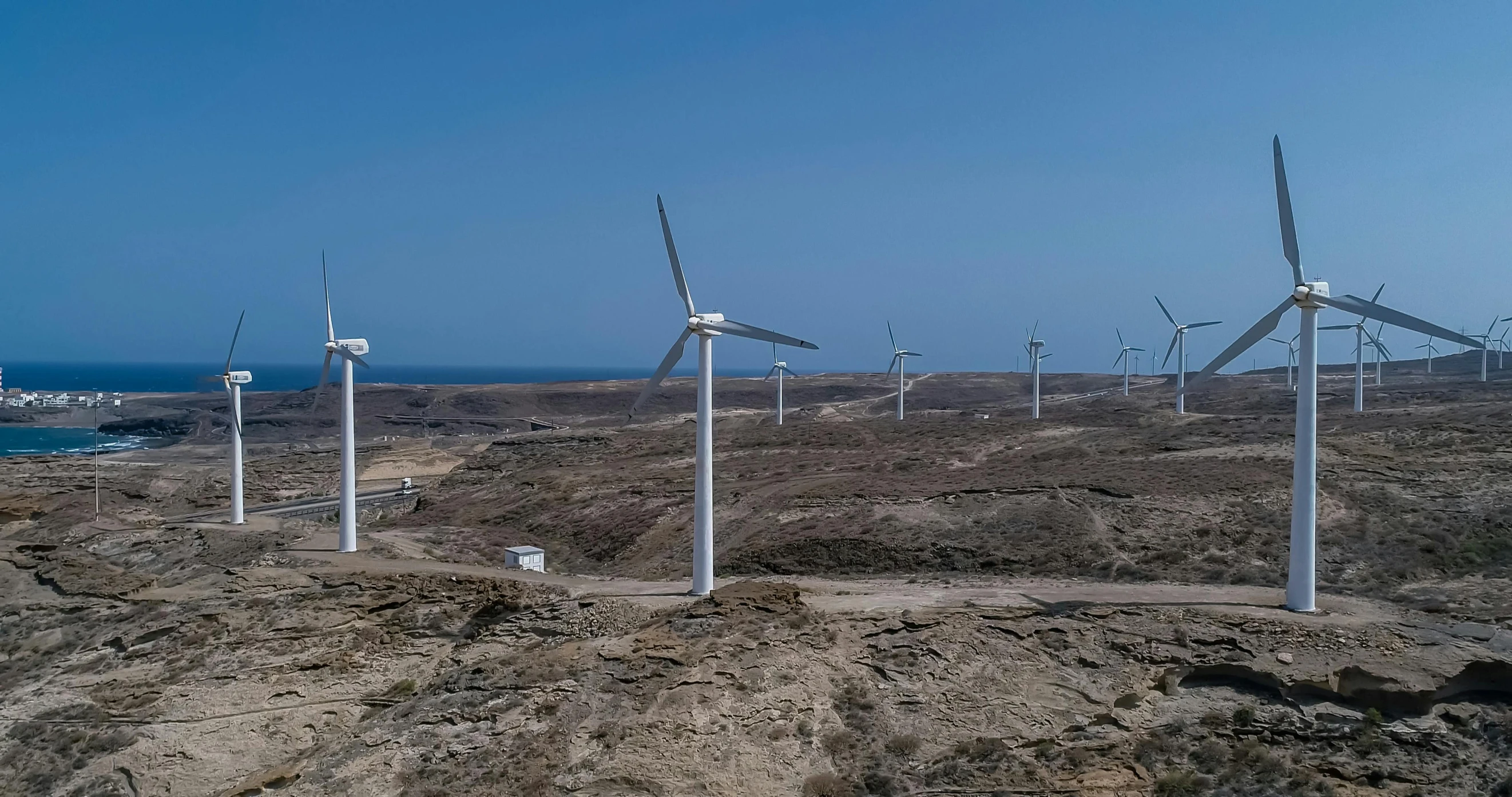 a group of wind turbines sitting on top of a rocky hillside, a portrait, pexels contest winner, hurufiyya, high quality product image”, desert white greenhouse, big island, panorama