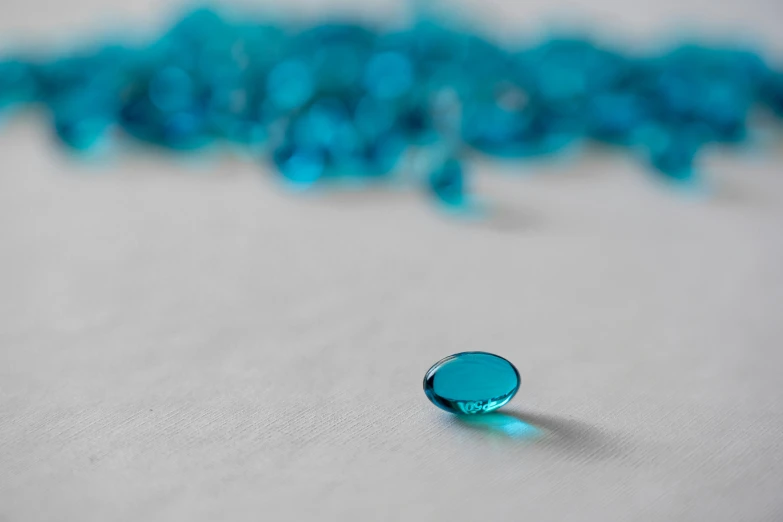 a close up of a glass object on a table, turquoise, micro lens, on a white table, phthalo blue