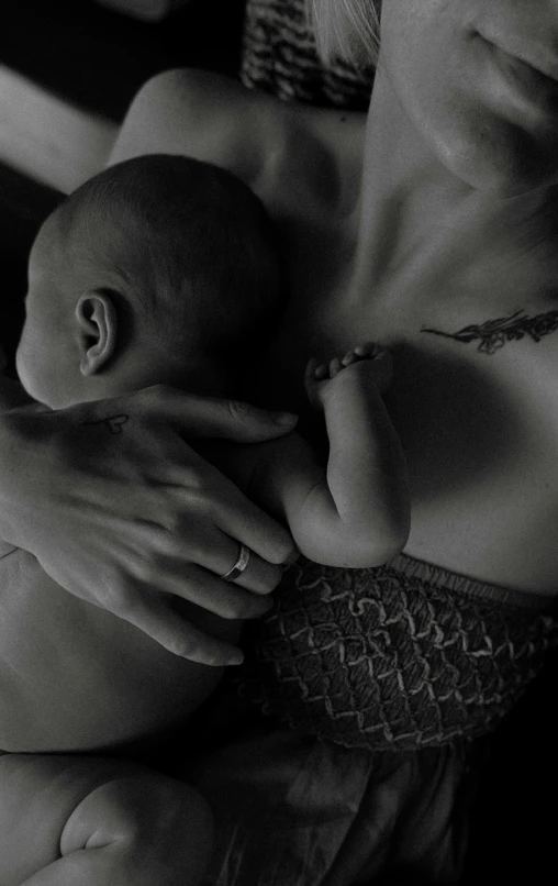 a woman holding a baby in her arms, a black and white photo, by Adam Marczyński, pexels, symbolism, nipple, die antwoord, epk, milk