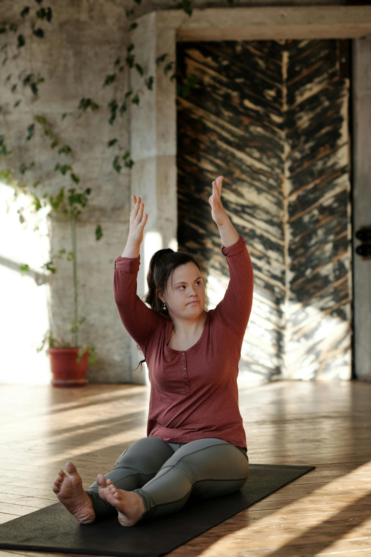 a woman sitting on a yoga mat doing a yoga pose, by Sigrid Hjertén, renaissance, with arms up, indoor setting, promo image, in the center of the image