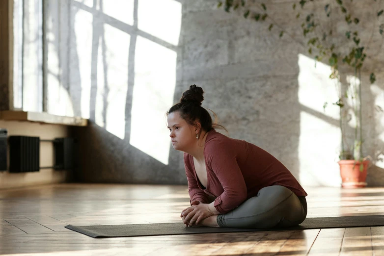 a woman sitting on a yoga mat in a room, pexels contest winner, bending down slightly, manuka, full figured, profile image