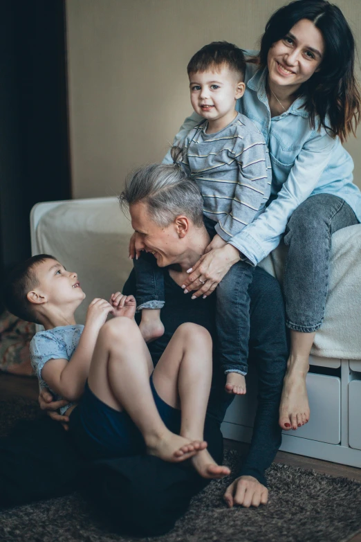 a woman sitting on top of a bed next to two boys, pexels contest winner, incoherents, father with child, hugging each other, profile image, grandfatherly