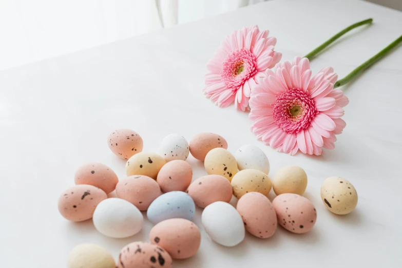 a bunch of eggs sitting on top of a table next to a pink flower, on a white table, candy - coated, high quality product image”, varying dots