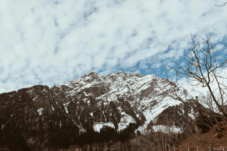 a man riding a snowboard down a snow covered slope, a picture, pexels contest winner, visual art, background image, trees and cliffs, tall fluffy clouds, himalayas