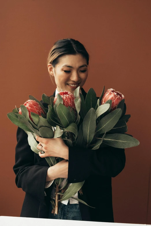 a woman holding a bunch of red flowers, inspired by helen huang, trending on unsplash, in shades of peach, studio photo, feels good man, made of flowers