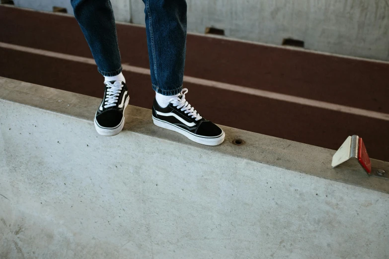 a person standing on the edge of a skateboard ramp, unsplash contest winner, running shoes, white and black, long thin legs, high arches