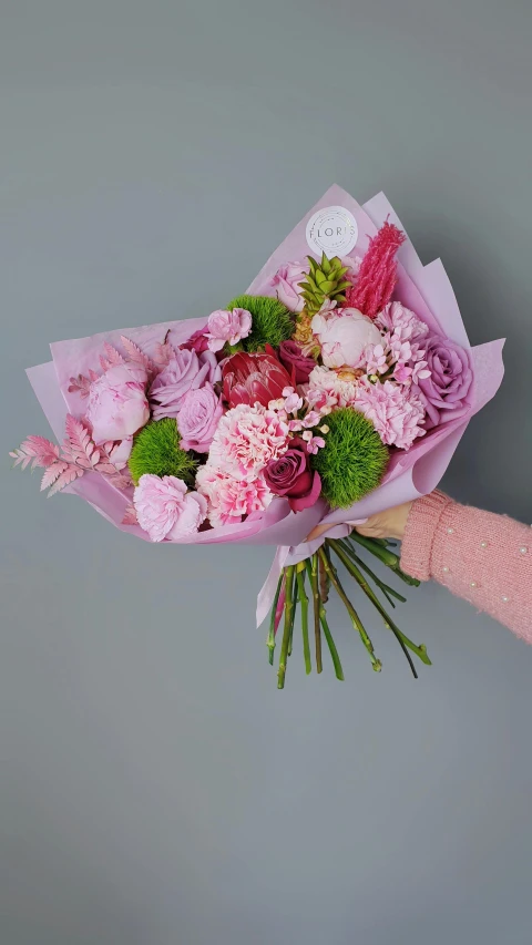a person holding a bouquet of pink and green flowers, on grey background, chrysanthemum and hyacinth, brilliantly coloured, award winning