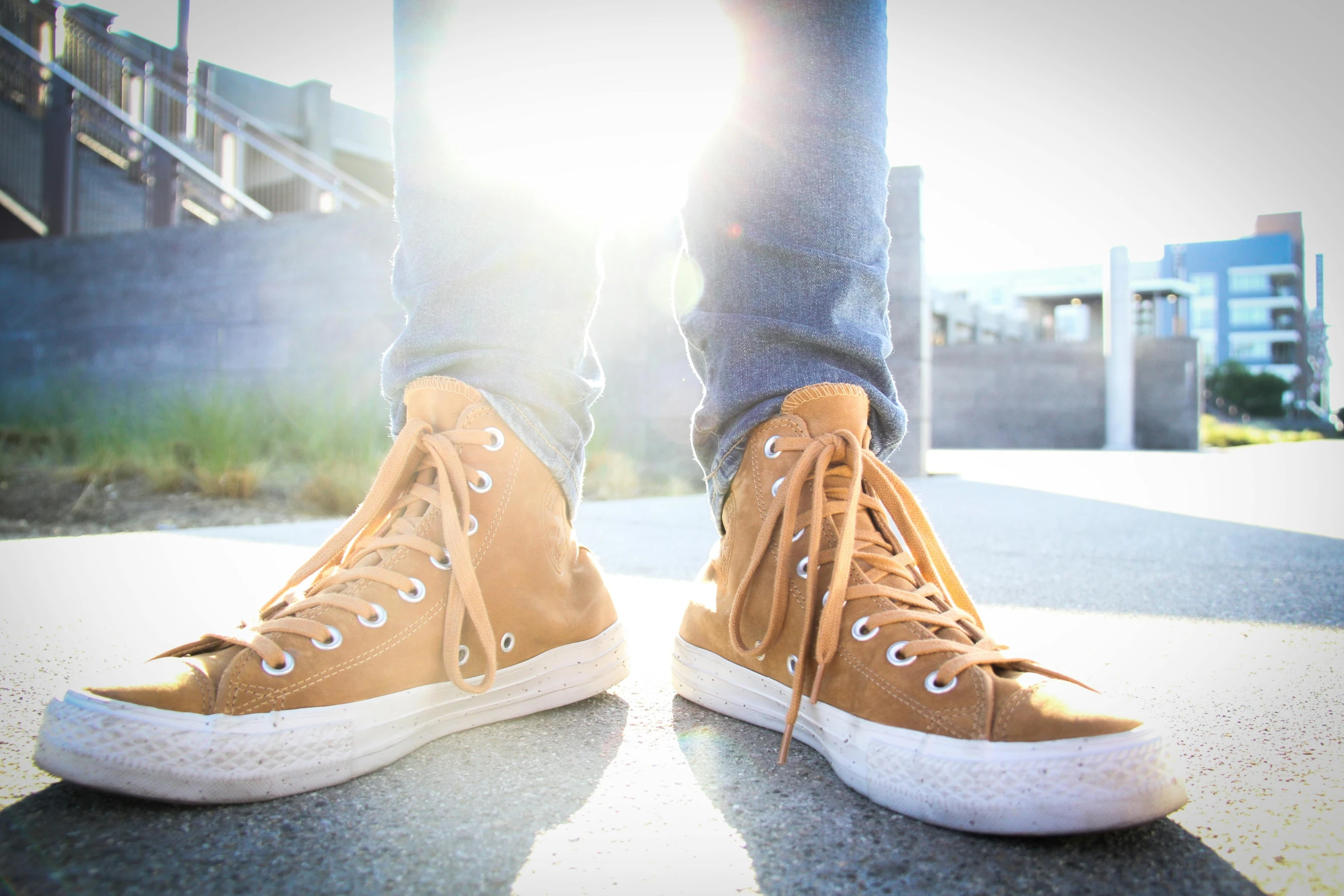 a close up of a person's shoes on a sidewalk, pexels, light brown colors, sun flairs, converse, leather and suede