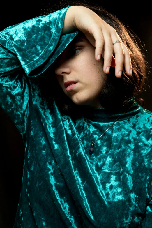 a close up of a person holding a cell phone, an album cover, inspired by Elsa Bleda, private press, dressed in a green robe, portrait androgynous girl, teal, brocade