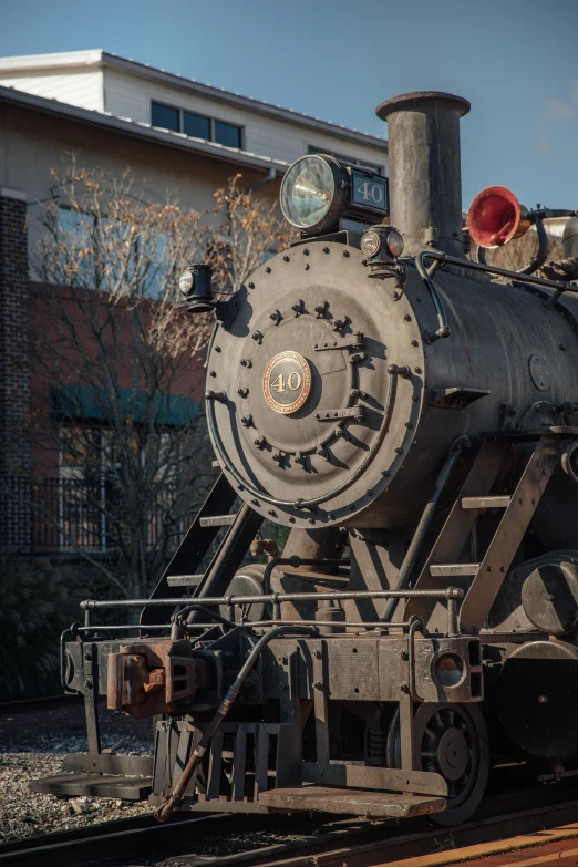 a train traveling down train tracks next to a building, steam engine, in savannah, headshot, on display