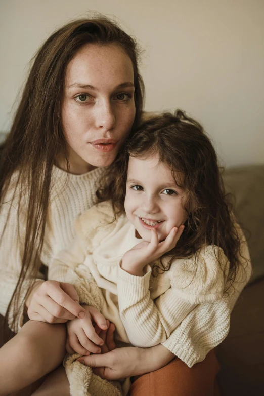 a woman sitting next to a little girl on a couch, by Adam Marczyński, pexels contest winner, renaissance, lovingly looking at camera, soft warm light, woman with braided brown hair, winter season