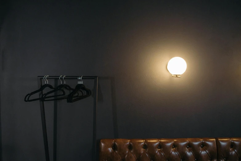 a brown leather couch in a dark room, inspired by Elsa Bleda, bauhaus, rgb wall light, glass bulbs, on a large marble wall, (night)