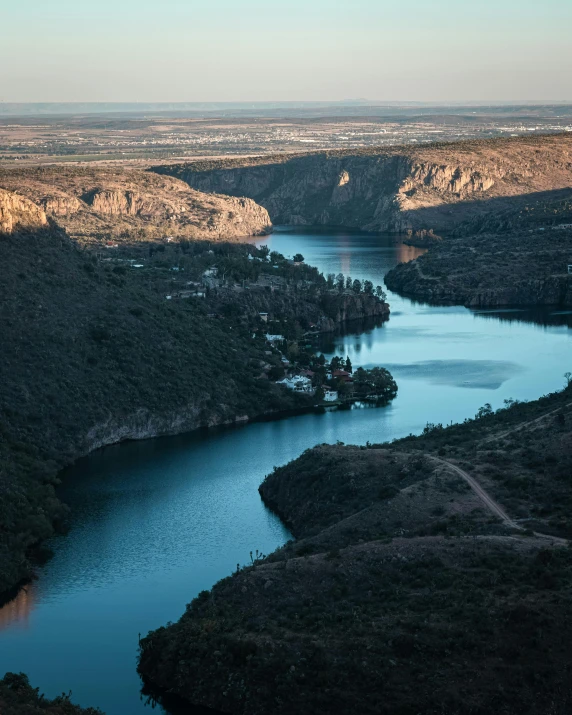 a large body of water sitting on top of a lush green hillside, by Peter Churcher, pexels contest winner, hurufiyya, guanajuato, slate, lake blue, sundown