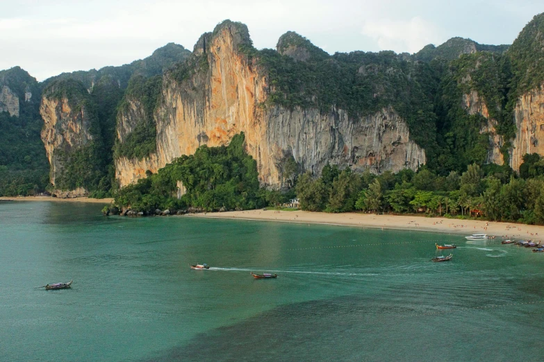 a group of boats floating on top of a body of water, inspired by Steve McCurry, pexels contest winner, hurufiyya, sharp cliffs, thai, beach is between the two valleys, youtube thumbnail