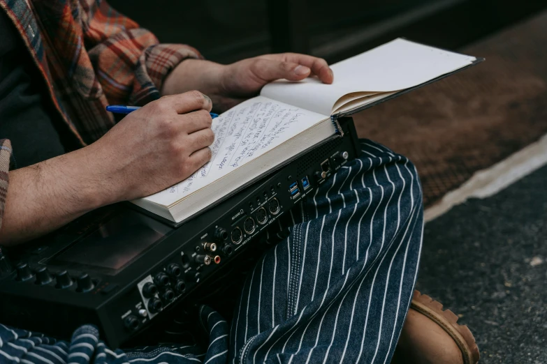 a person sitting on the ground with a laptop and a notebook, an album cover, by Carey Morris, pexels contest winner, happening, lined paper, closeup portrait, thumbnail, old school