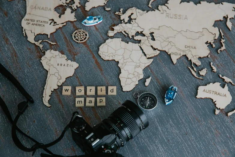 a camera sitting on top of a table next to a map, a jigsaw puzzle, board games, pyrography, close up photograph, world map