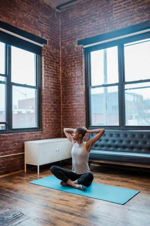 a woman sitting on a yoga mat in a living room, by Carey Morris, unsplash contest winner, tall windows, square, working out, boston