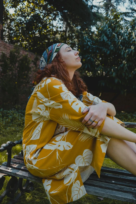 a woman sitting on top of a wooden bench, inspired by Elsa Bleda, pexels contest winner, renaissance, wearing yellow floral blouse, hippy, sleepy, a redheaded young woman