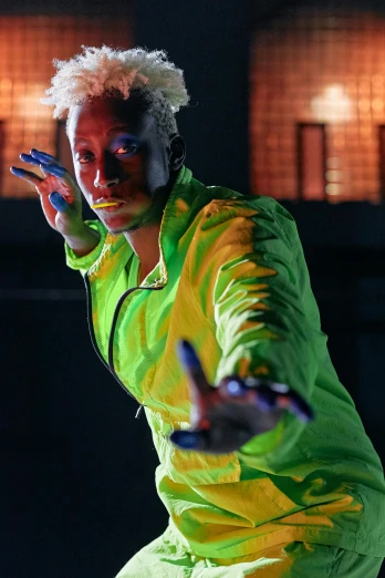 a man holding a tennis racquet on top of a tennis court, inspired by Gerard Sekoto, afrofuturism, neon colored suit, neon hair, performing on stage, model wears a puffer jacket
