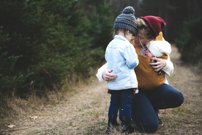 a woman kneeling next to a child in a field, pexels, beanie, hugging each other, hygge, rectangle