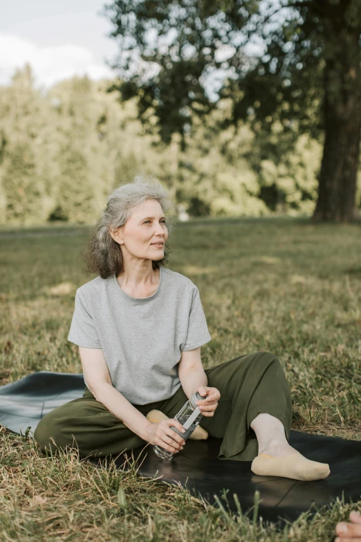 an older woman sitting on a yoga mat in a park, by Matija Jama, pexels contest winner, full body potrait holding bottle, 15081959 21121991 01012000 4k, profile picture, going gray