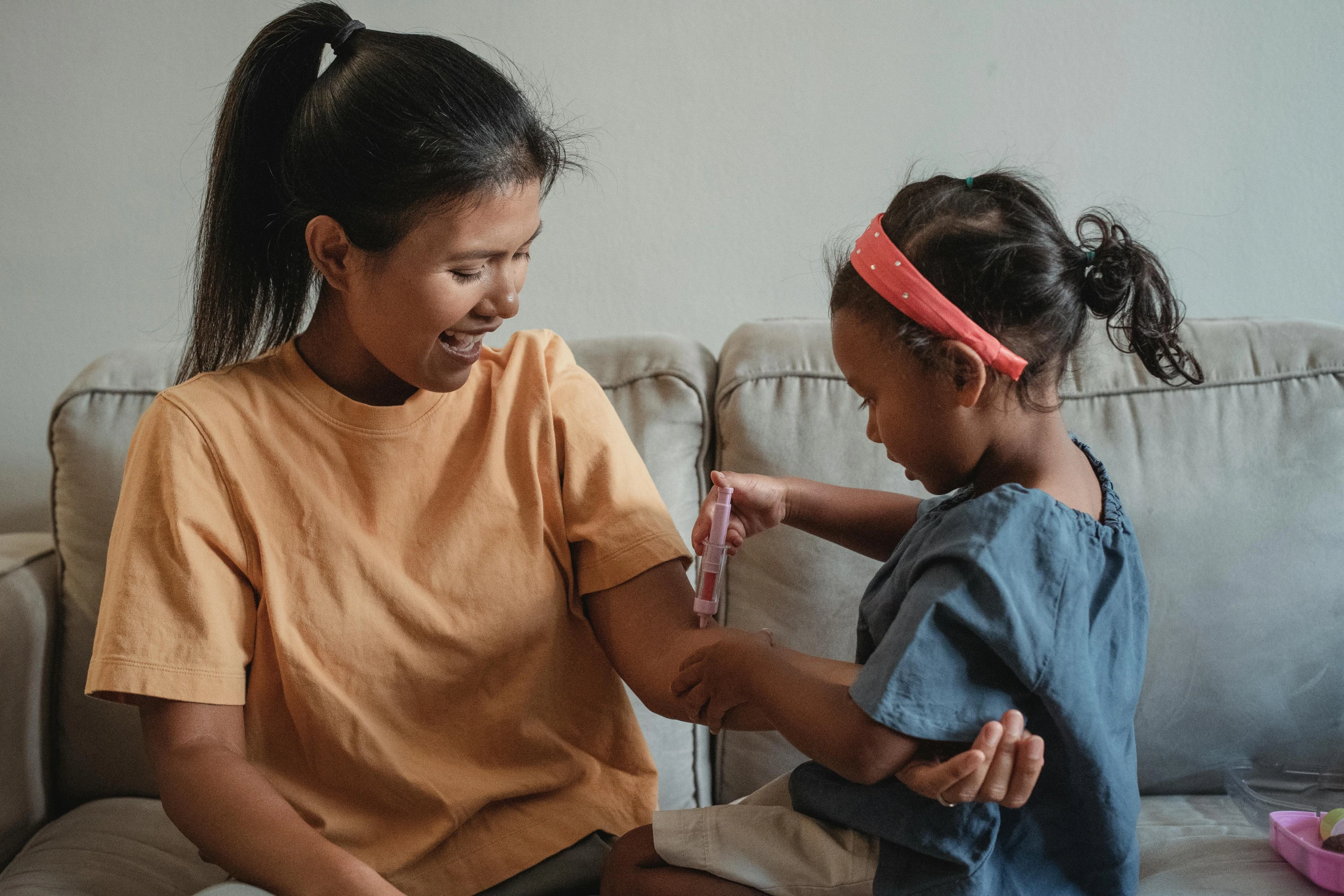 a woman and a little girl sitting on a couch, pexels contest winner, holding a syringe, manuka, black bandage on arms, profile image