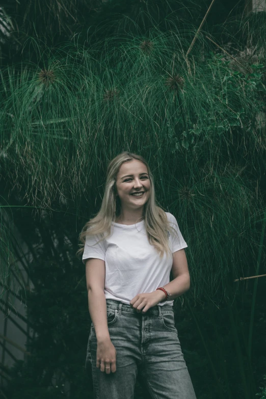 a woman standing in front of some tall grass, pexels contest winner, portrait of white teenage girl, solid background, bushes, lachlan bailey