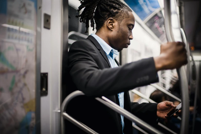 a man in a suit on a subway looking at his phone, by Carey Morris, pexels contest winner, dreadlock black hair, thumbnail, working, profile picture