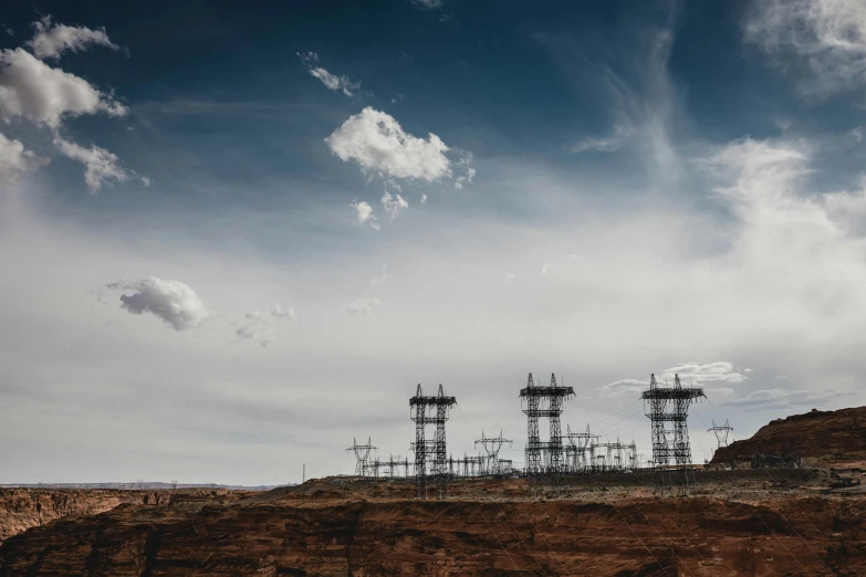 a group of power lines sitting in the middle of a desert, a matte painting, unsplash, moab, metal towers and sewers, cloudy skies, maintenance photo