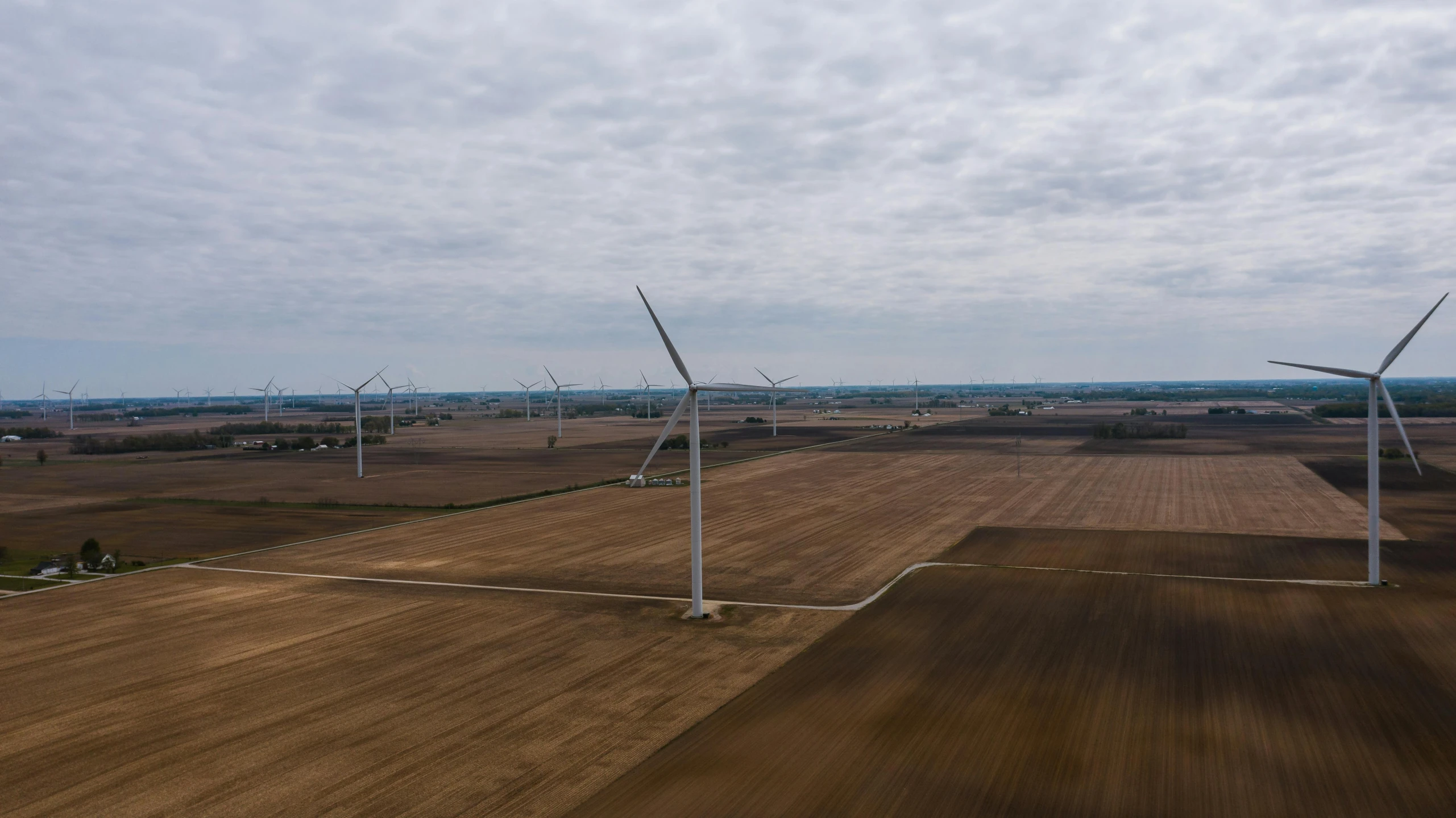 a group of wind turbines sitting on top of a field, by Jacob Burck, pexels contest winner, midwest town, ultrawide angle cinematic view, aerial footage, 15081959 21121991 01012000 4k