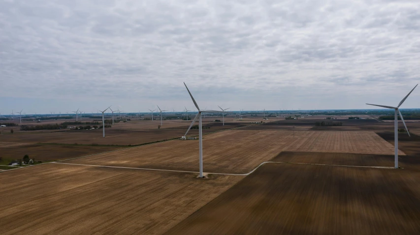 a group of wind turbines sitting on top of a field, by Jacob Burck, pexels contest winner, midwest town, ultrawide angle cinematic view, aerial footage, 15081959 21121991 01012000 4k