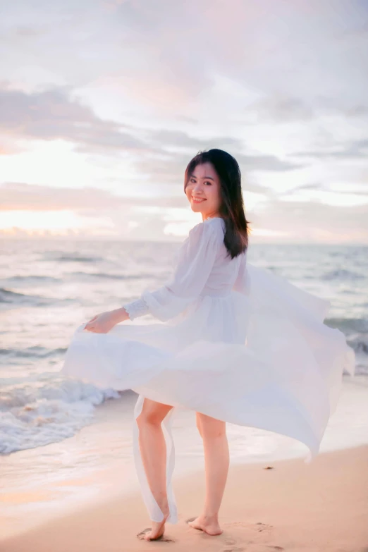 a woman standing on top of a beach next to the ocean, by Tan Ting-pho, romanticism, wearing a cute white dress, joyful look, 15081959 21121991 01012000 4k, wearing a long flowy fabric
