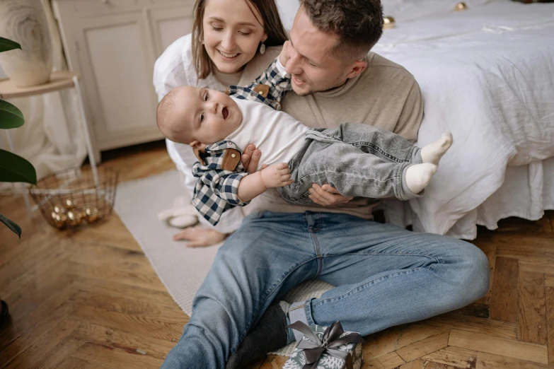 a man and woman sitting on the floor with a baby, pexels contest winner, 268435456k film, handsome man, decoration, father holds child in the hand