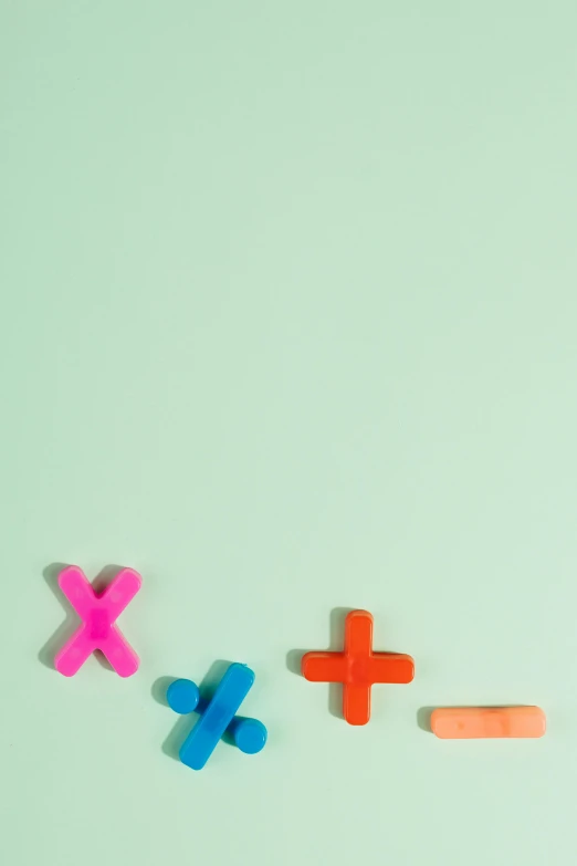 a group of colorful magnets sitting on top of a green surface, a digital rendering, by Daniel Seghers, trending on pexels, math equations, crosses, pink and teal color palette, ox
