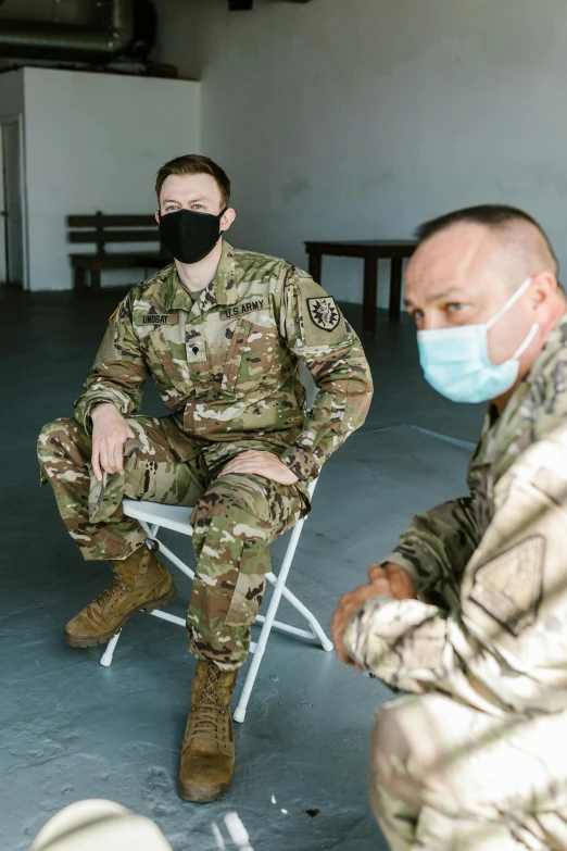 a couple of men sitting on top of a chair, army uniform, face mask, medic, lgbtq