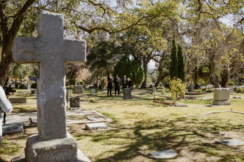 a group of people standing around a cemetery, by Winona Nelson, unsplash, avatar image, actor, bottom angle, ignant