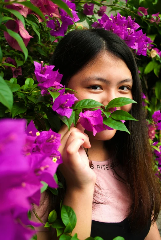 a girl holding a purple flower in front of her face, inspired by Tan Ting-pho, pexels contest winner, sumatraism, bougainvillea, teenager, made of flowers, low quality photo