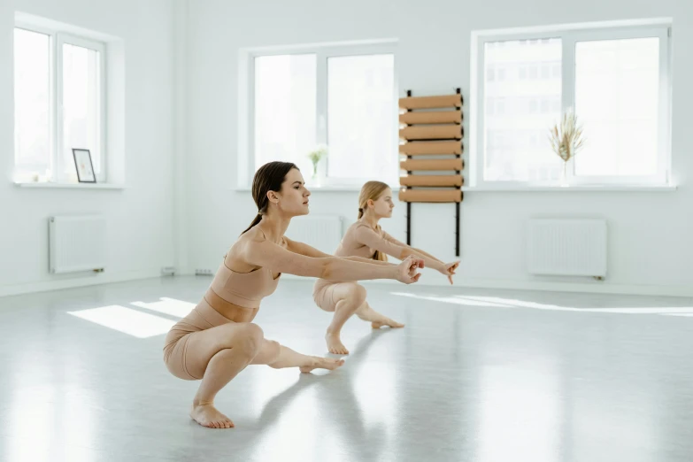 a woman and a baby in a white room, arabesque, athletic muscle tone, sitting on bent knees, best practice, squatting