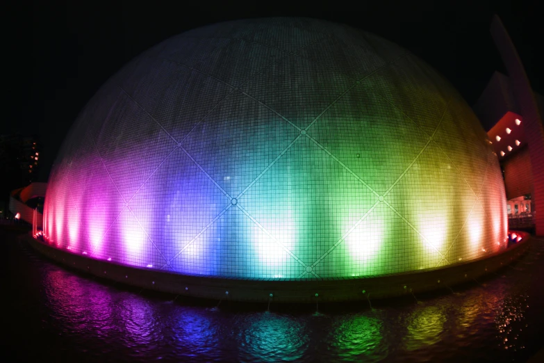 a brightly lit water fountain in front of a building, a hologram, inspired by Bruce Munro, trending on unsplash, interactive art, dome, 2 5 6 x 2 5 6 pixels, just one rainbow 8 k, hexadome