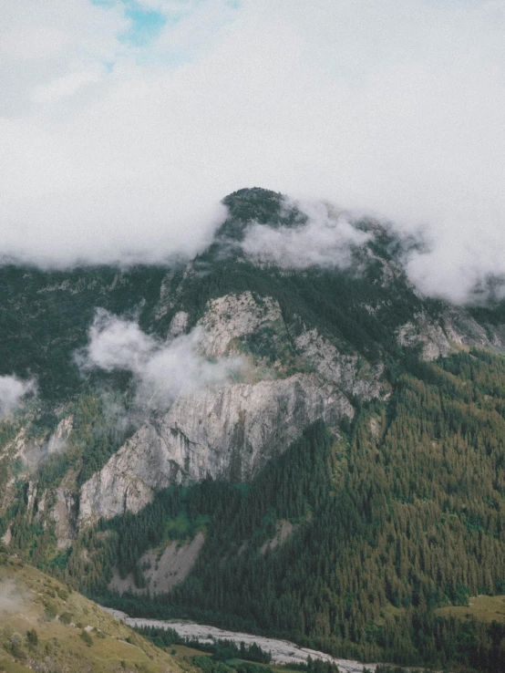 a man standing on top of a lush green hillside, pexels contest winner, ominous! landscape of north bend, “ aerial view of a mountain, grey, covered in clouds