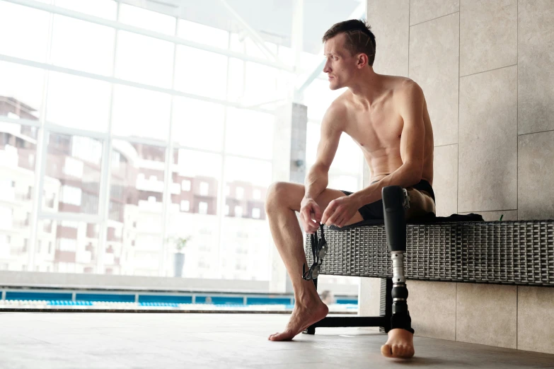 a man sitting on a bench next to a swimming pool, a portrait, shutterstock, prostheses, exoskeletton, sitting on the floor, portait image