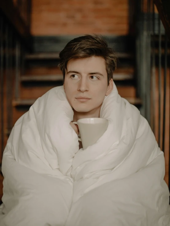 a man wrapped up in a blanket holding a cup, an album cover, inspired by Louis Hersent, young face, anton fadeev 8 k, gif, low quality photo