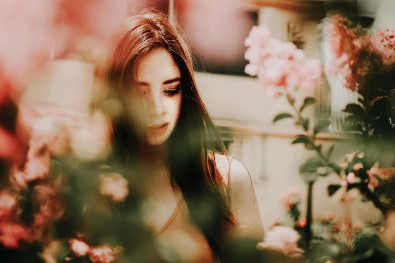 a woman standing in front of a bunch of flowers, a picture, inspired by Elsa Bleda, trending on pexels, romanticism, girl with dark brown hair, blurry face, attractive face and body, shades of pink