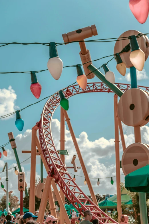 a group of people standing in front of a roller coaster, hanging lanterns, sunlight and whimsical houses, retro lights, upclose